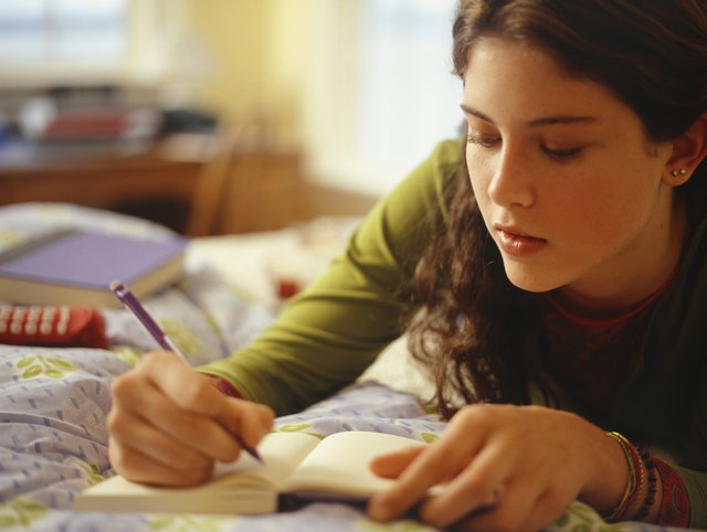 Teenage girl (16-17) lying on bed, writing, close-up