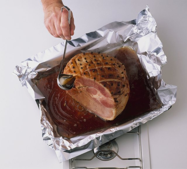 Person basting roast ham, using ladle, close-up