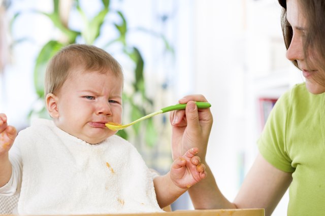 Unhappy baby boy refusing to eat food.