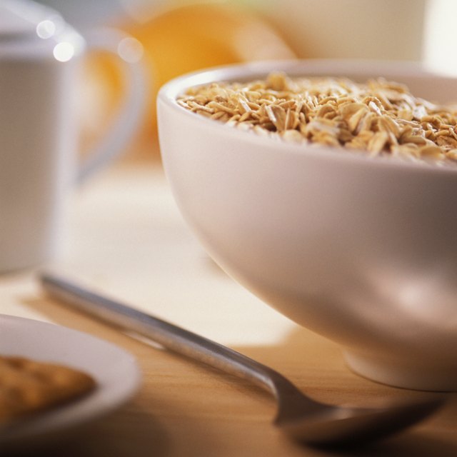 Bowl of cereal with spoon and edge of plate with pastry on it, close-up