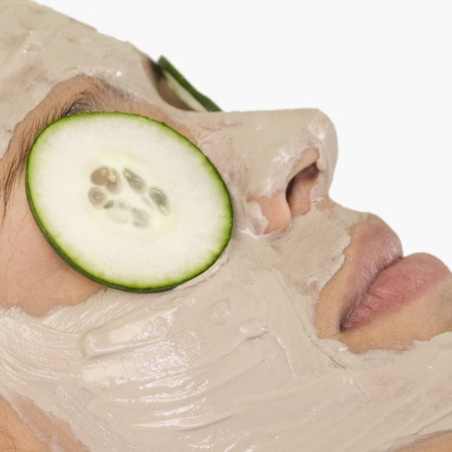 Young woman with mud mask and cucumber slices on eyes