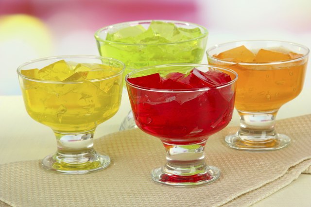 Tasty jelly cubes in bowls on table on light background