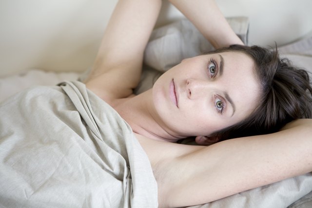pensive brunette woman lying on bed