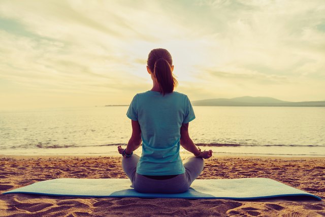 Girl meditating in pose of lotus on beach