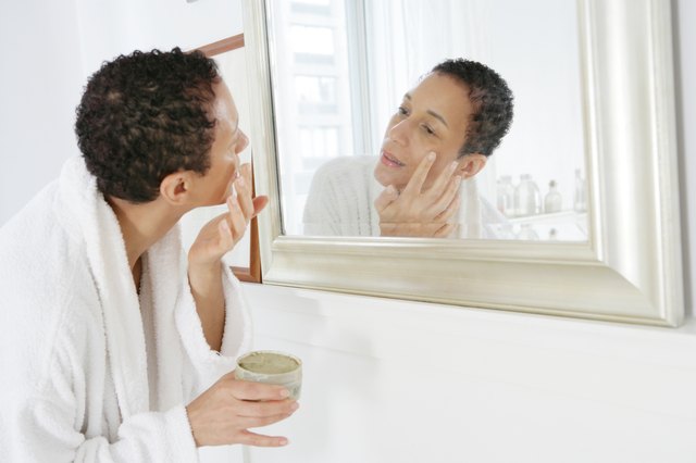 African American woman applying face mask.