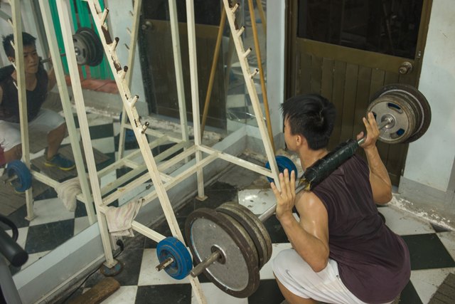 Muscular man weightlifting, exercising very hard in the gym