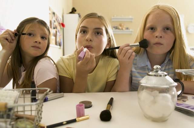 teenage lifestyle shot of three female friends as they sit at a vanity and put on make up