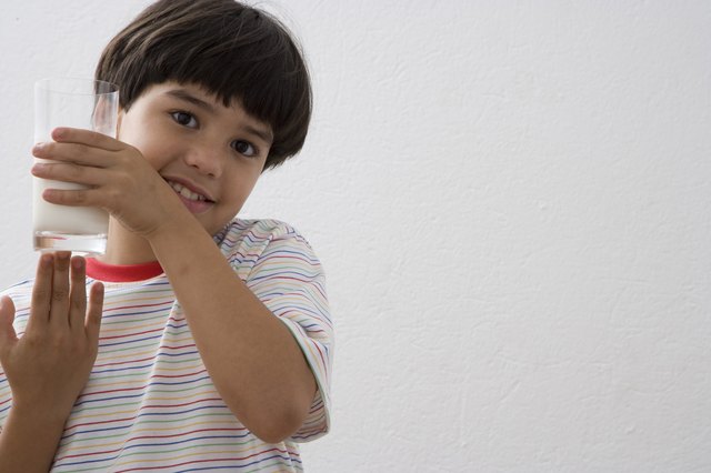 Boy (8-9) holding glass of milk, portrait