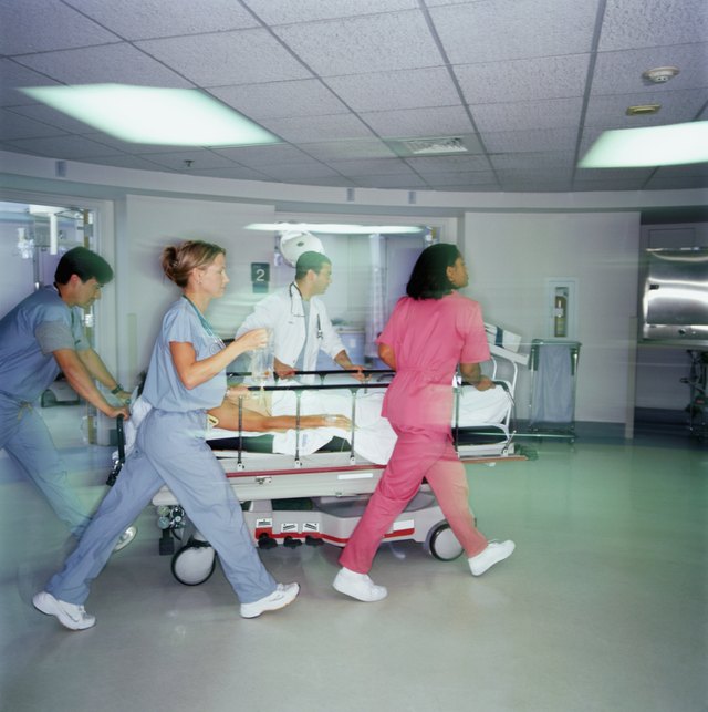 Doctors and nurses pushing patient on gurney through emergency room