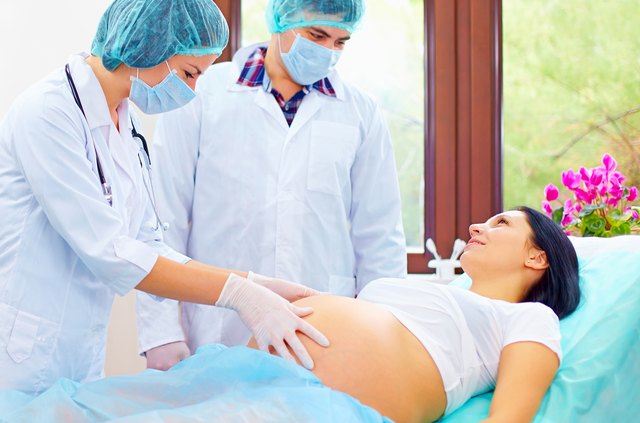 doctor palpates the abdomen of pregnant woman before childbirth