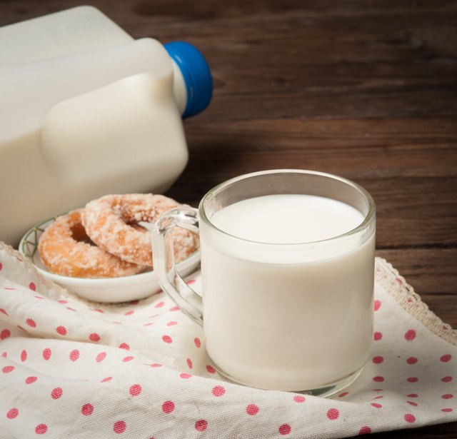 Glass of milk with doughnut on wood