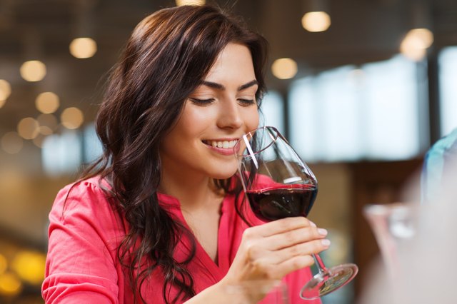 smiling woman drinking red wine at restaurant