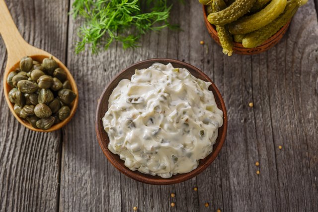 tartar sauce in a gravy boat on a wooden surface