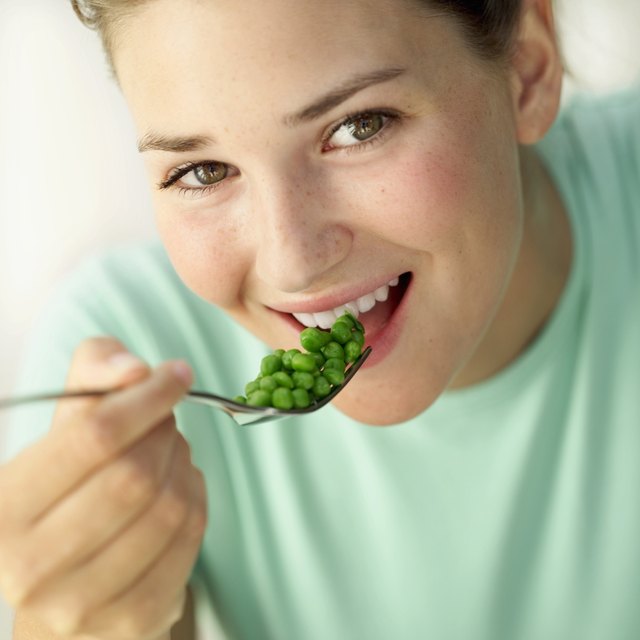 Close-up of a woman eating peas with a fork