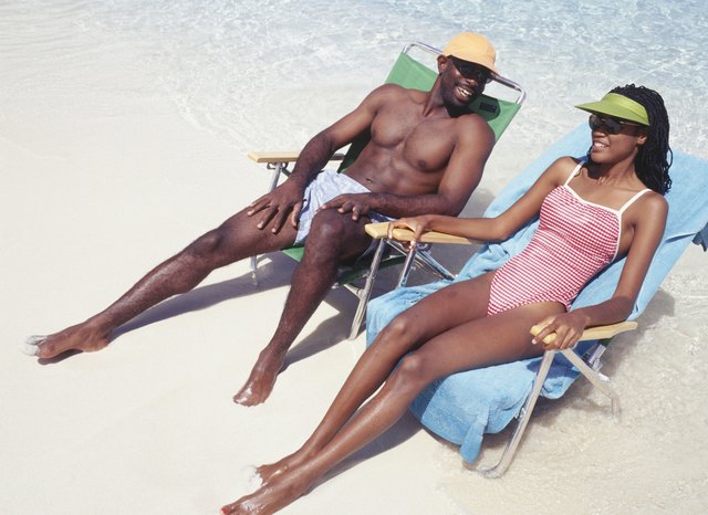 Man and woman sunbathing in deckchairs on beach, elevated view