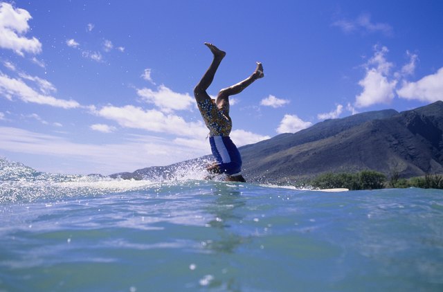 Man standing on head on surfboard at ocean
