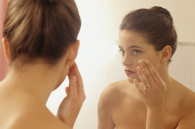 Young woman in bathroom, doing make up in front of mirror, close-up