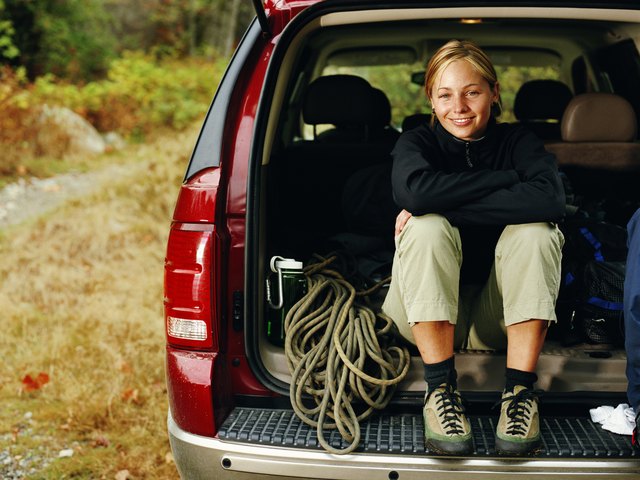 Femal rock climer sitting with gear in back of SUV, portrait