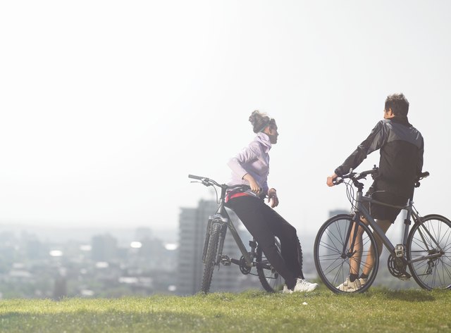 Man and woman talking while resting on hill after bike ride
