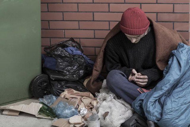 Sad homeless man sitting on the trash