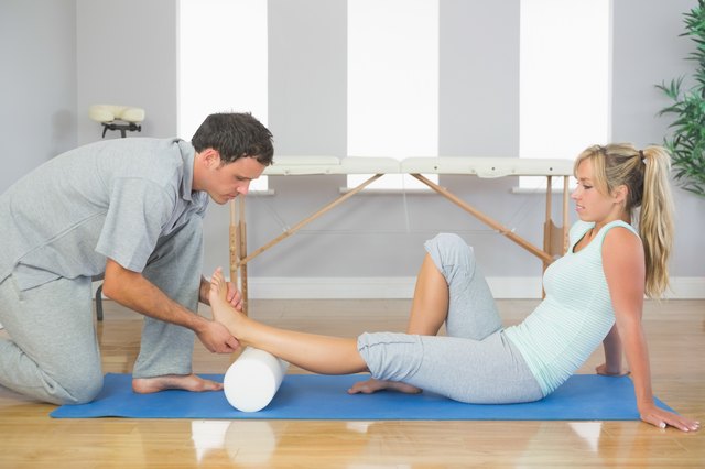 Physiotherapist examining patients foot while sitting on floor