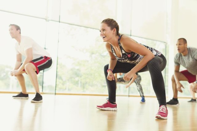Smiling woman squatting in aerobics class
