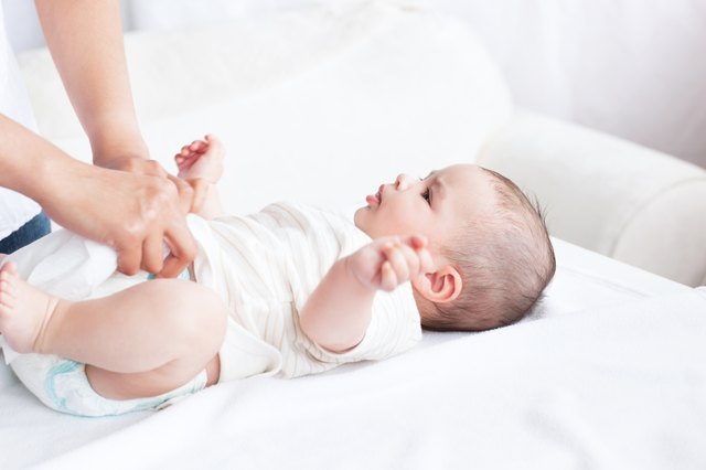 Close-up of a young mother changing the nappy of her baby lying on a couch