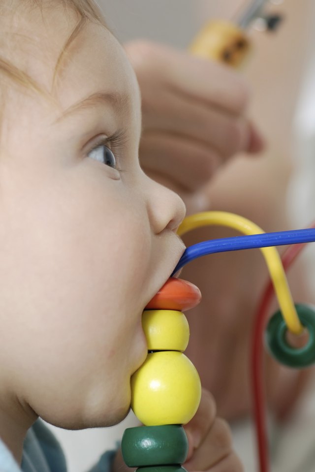 baby eating a wooden toy