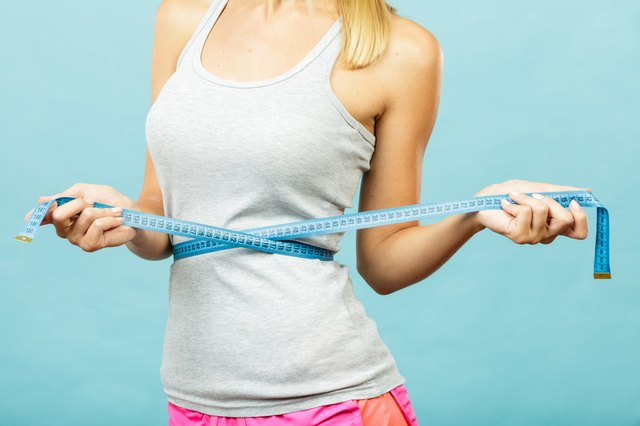 Fitness girl measuring her waistline