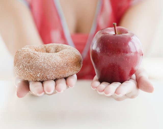 "Woman holding out donut and apple, close up"