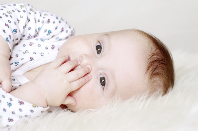five-months baby closes mouth with hand