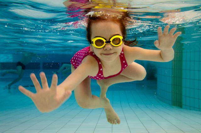 Girl smiles, swimming under water in the pool