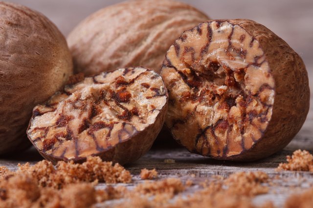 sliced and grated nutmeg on an old wooden table