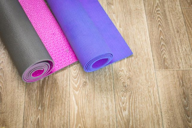 Two Yoga mats (pink and purple) on a wooden background