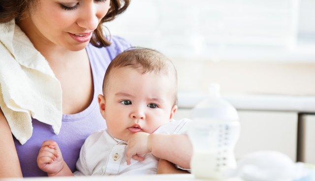 Portrait of a charming mother taking care of her adorable baby in the kitchen