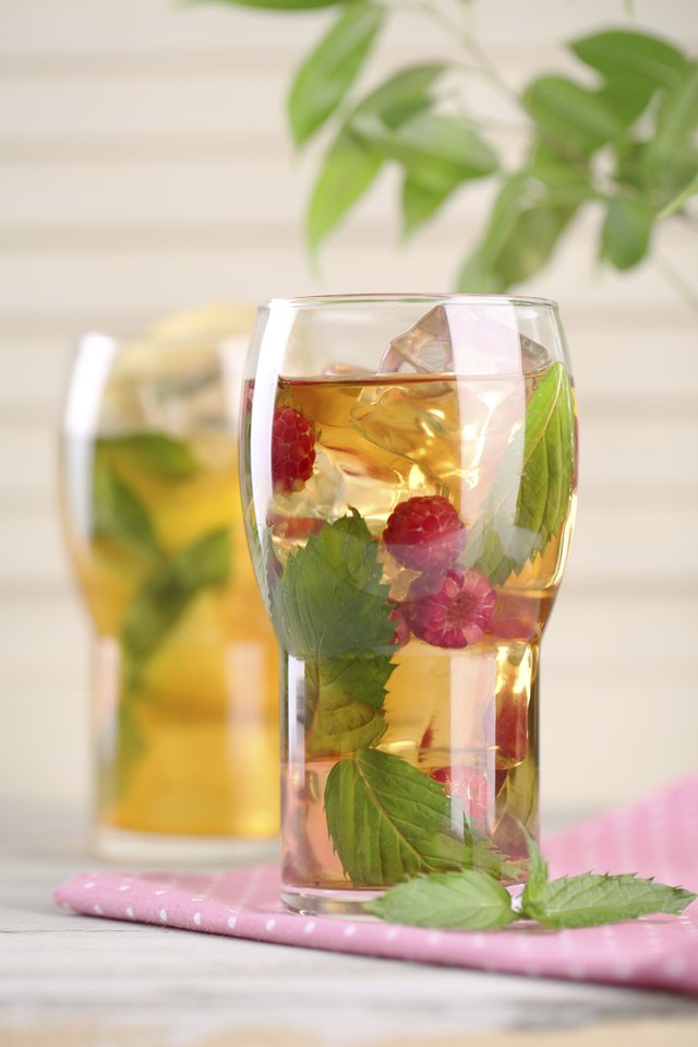 Iced tea with raspberries, lemon and mint on wooden table