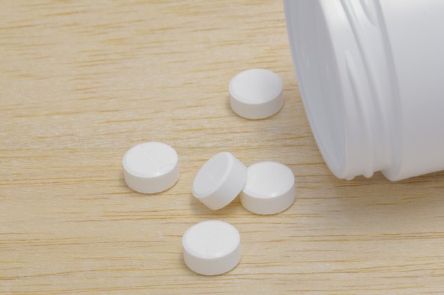 Pills spilling out of pill bottle on wood back ground