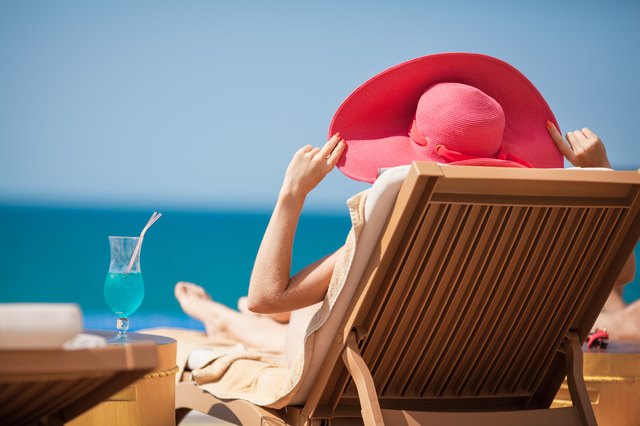 Woman in hat on a sun lounger near the sea