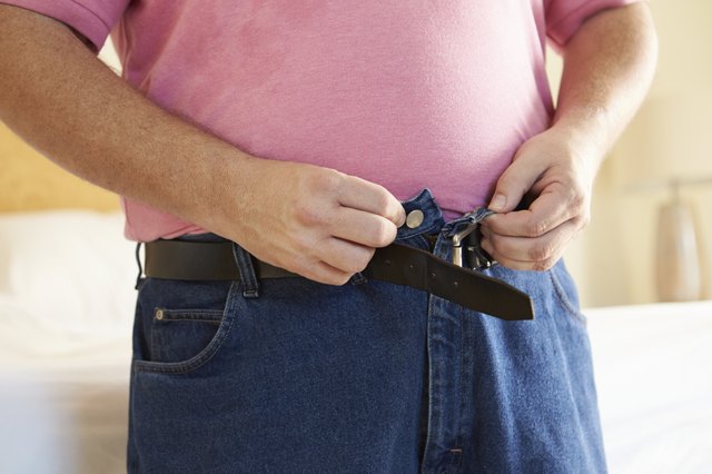 Close Up Of Overweight Man Trying To Fasten Trousers