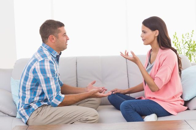 Side view of man and woman arguing while sitting on sofa at home