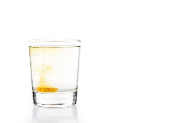 Effervescent vitamin C tablet bubbles in glass of water