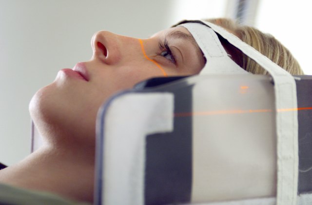 close up of a blonde caucasian female patient as her head is strapped into a cat scan machine