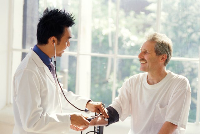 portrait of a young male doctor checking a patient's blood pressure