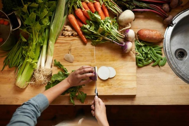 High angle shot of a woman cutting up vegetables on a cutting board