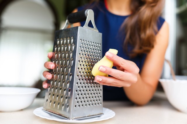 Young woman grating ginger