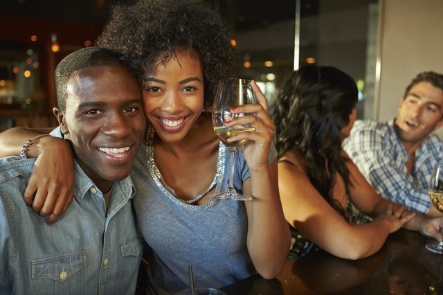 Couple Enjoying Drink At Bar With Friends