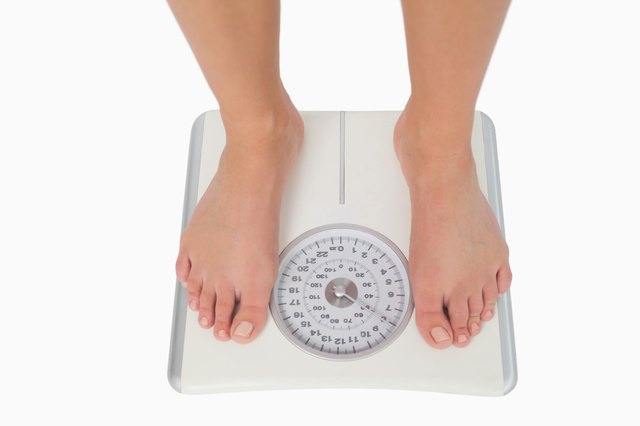 Female feet standing on a white scales