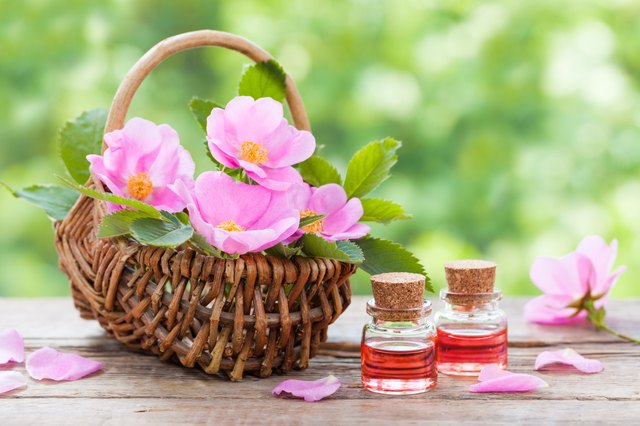 Basket with pink rose hip flowers and bottles of oil