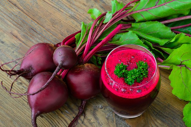 Glass of fresh beetroot juice with bets on wooden table