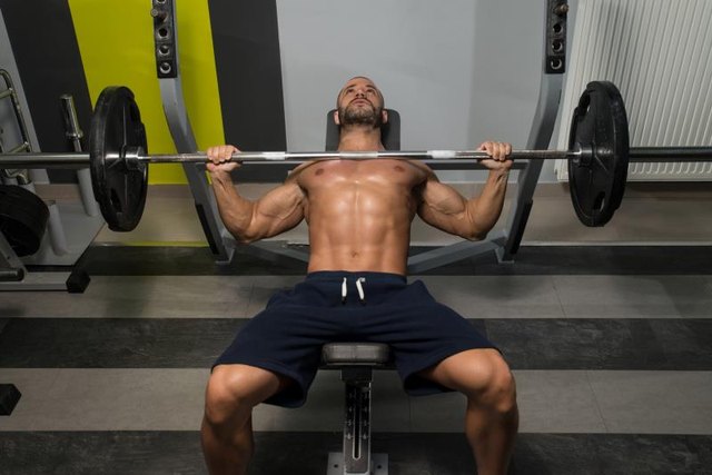 Young Man In Gym Exercising Chest On The Bench Press